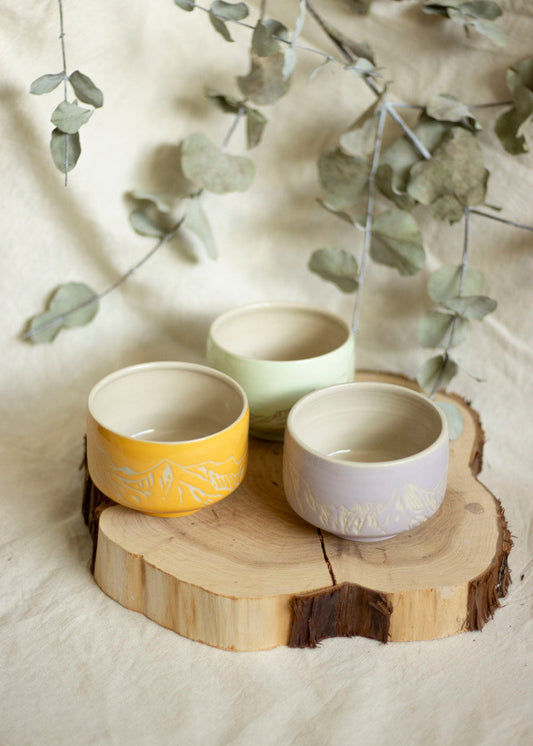 Image d'un trio de bols à thé aux couleurs Lilas, Mint et Orange doux. Ces bols utilisent la technique du sgraffito et sont gravés de paysages de Montagnes