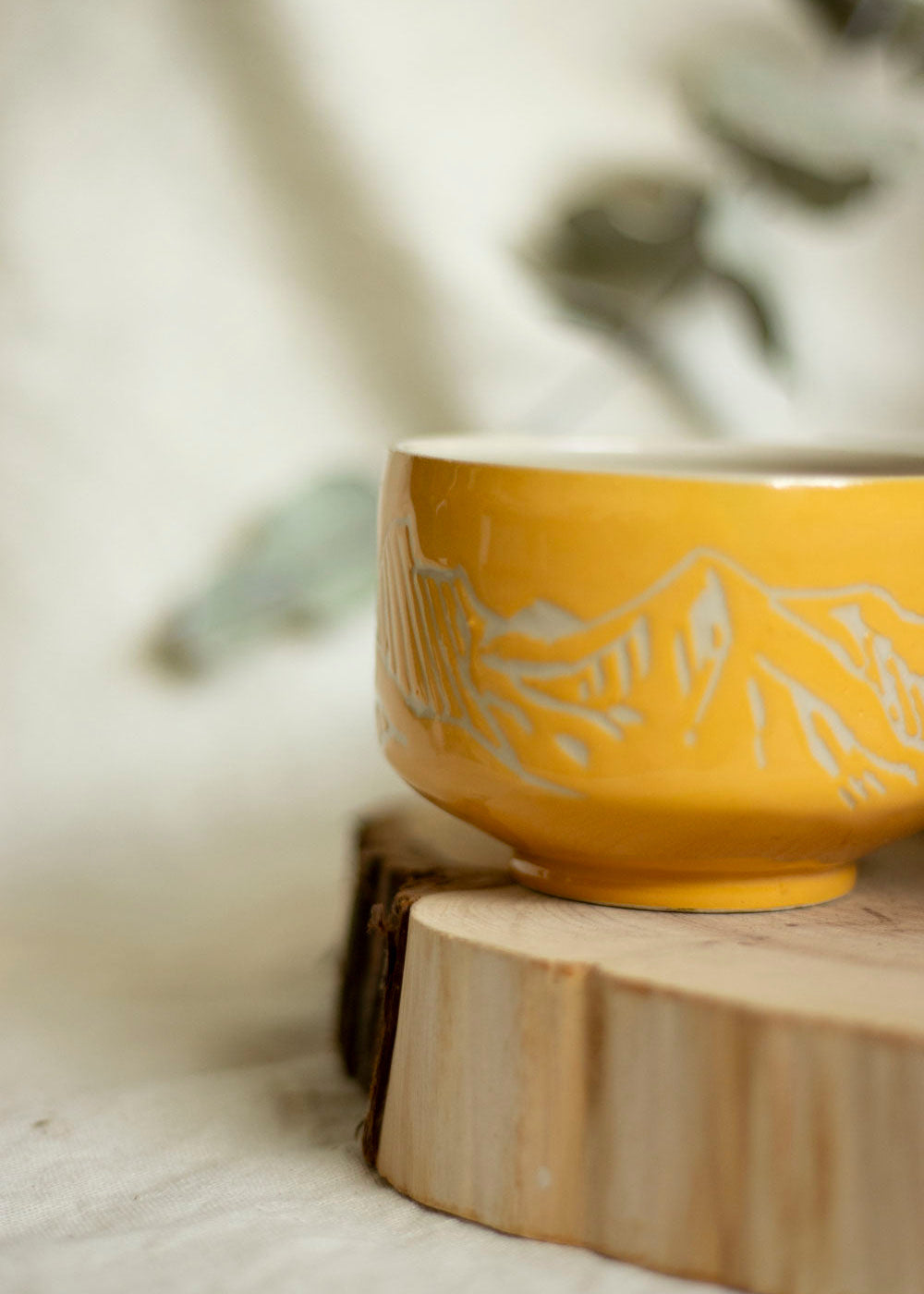 Image d'un bol à thé orange. Le bol est décoré en utilisant la technique du sgraffito et est gravé de paysages de Montagnes.