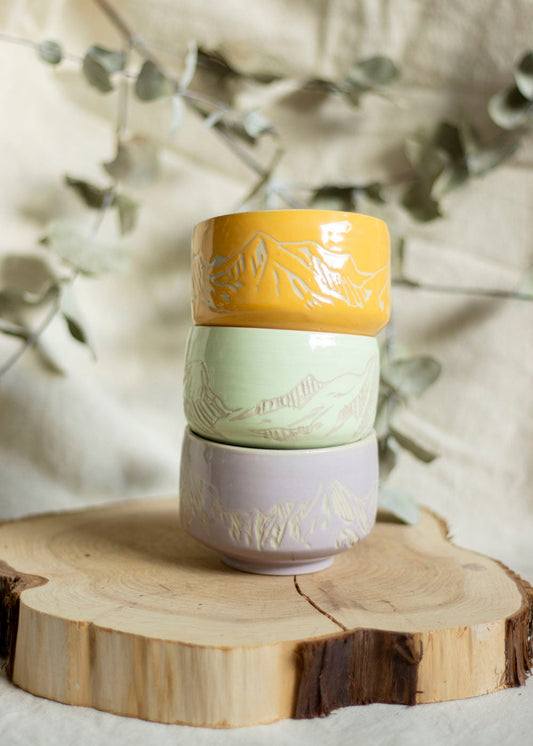 Image d'un trio de bols à thé aux couleurs Lilas, Mint et Orange doux. Ces bols utilisent la technique du sgraffito et sont gravés de paysages de Montagnes
