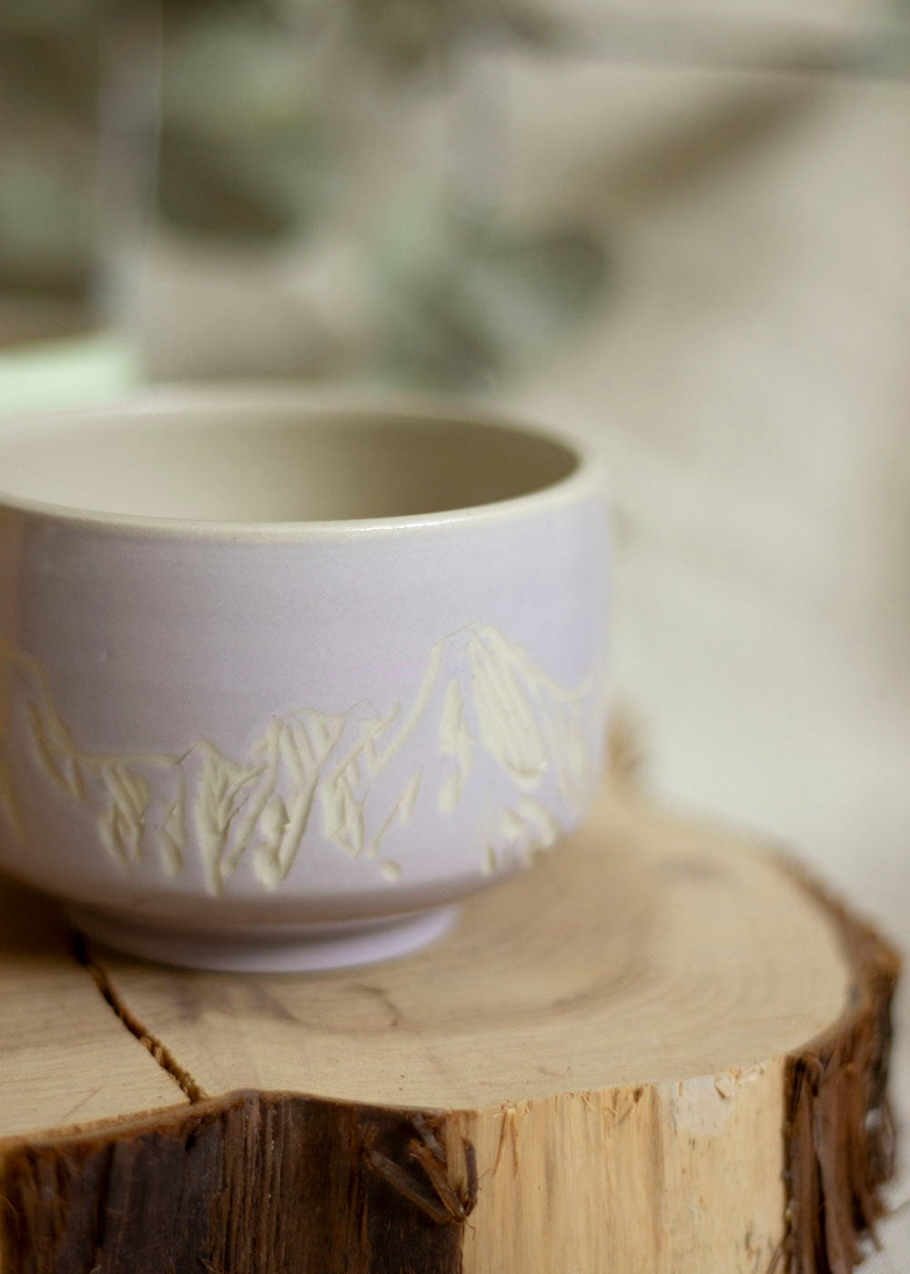 Image d'un bol à thé lilas. Le bol est décoré en utilisant la technique du sgraffito et est gravé de paysages de Montagnes. 